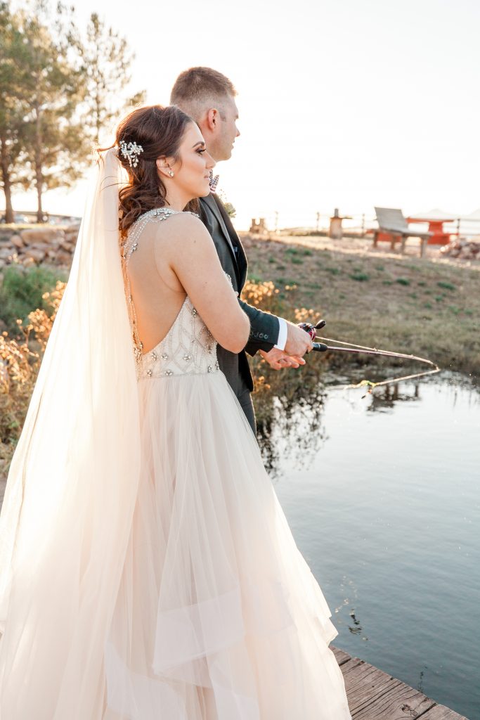 Bride and groom fishing on a pond